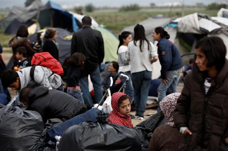 Una familia espera a ser trasladada a otros centros de recogida durante el desalojo del campamento de refugiados de Idomeni.