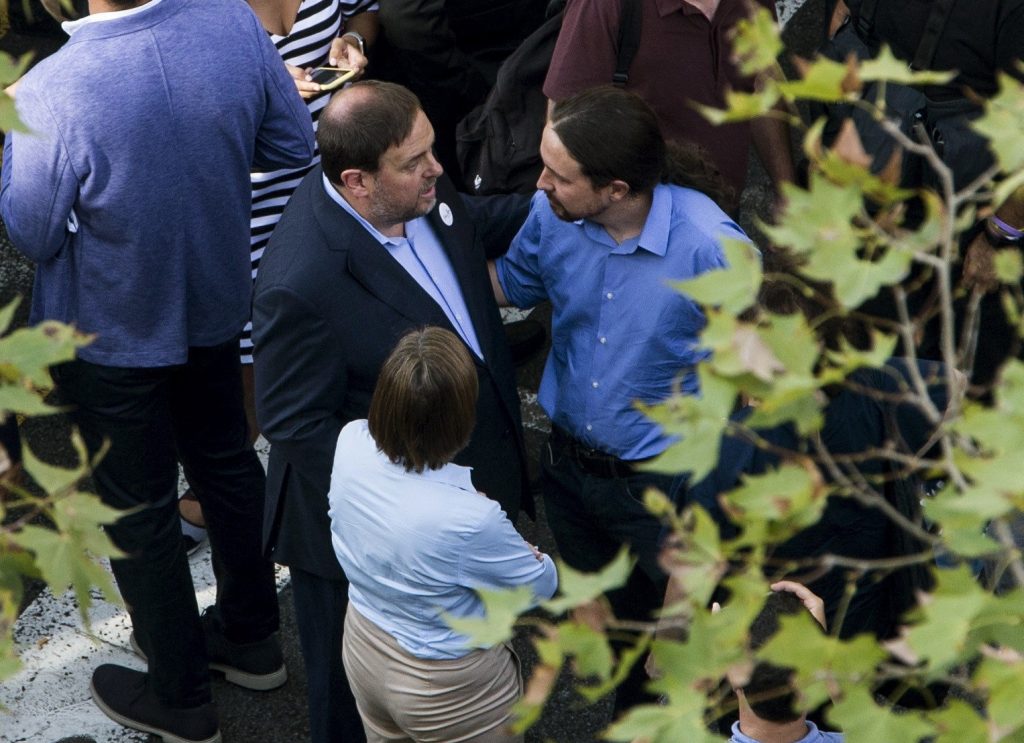 Oriol Junqueras, con chaqueta, vicepresidente de la Generalitat de Catalunya, conversa con Pablo Iglesias, a la derecha de la imagen, con camisa azul, secretario general de Podemos, en un momento de la manifestación celebrada el pasado 26 de junio en Barcelona, en contra del terrorismo