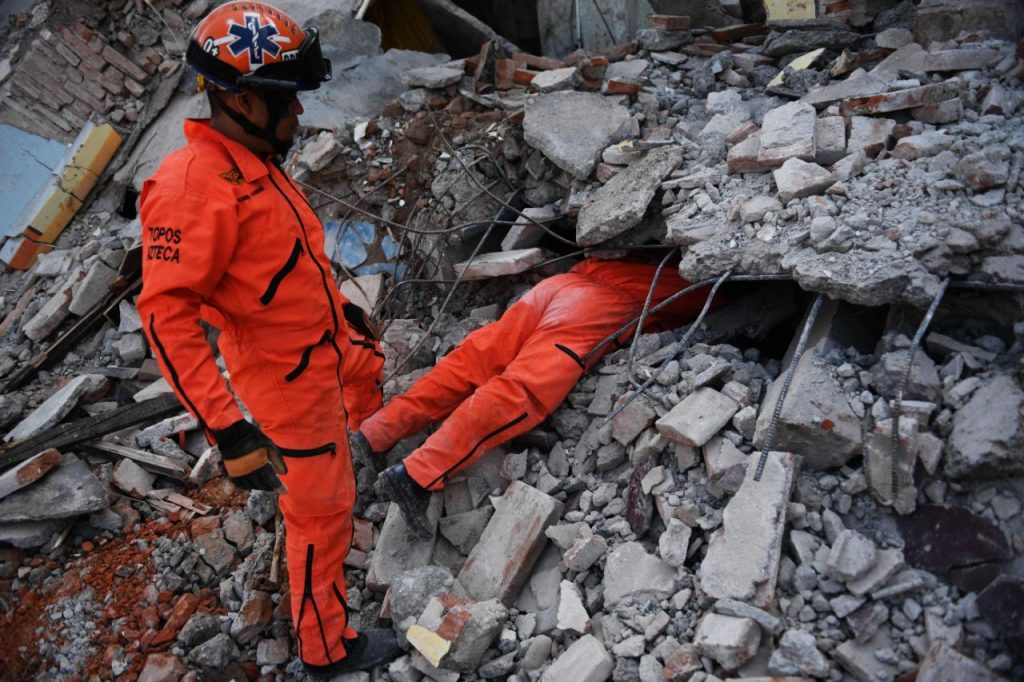 Un equipo de Topos Azteca se introduce en un edificio derrumbado a través de una grieta.