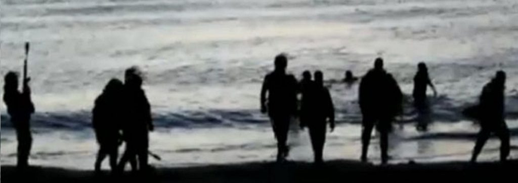 Captura del vídeo donde se ve a unos inmigrantes cruzando a nado la frontera y a unos agentes, en tierra.