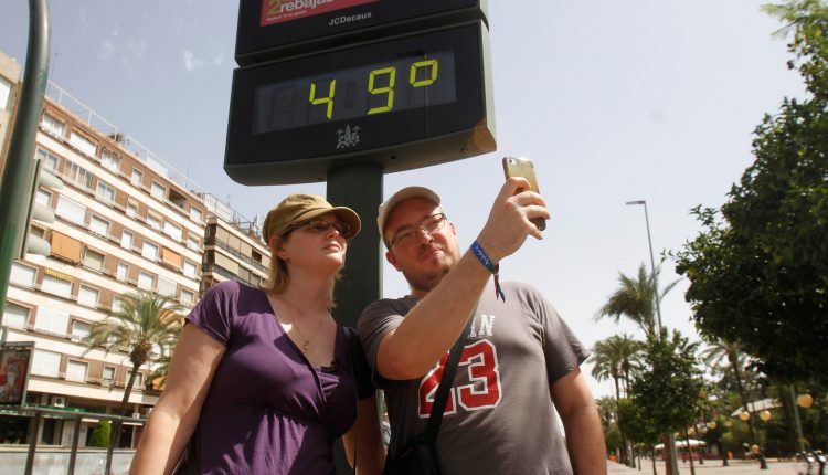 Turistas se hacen una foto junto a un termómetro de Córdoba que marca 49ºC debido a la ola de calor de los últimos días.